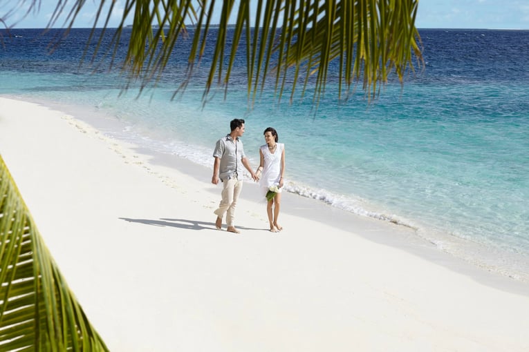 Dusit Thani Maldives dusit-thani-maldives_wedding_couple-on-beach-with-palm-leaves1